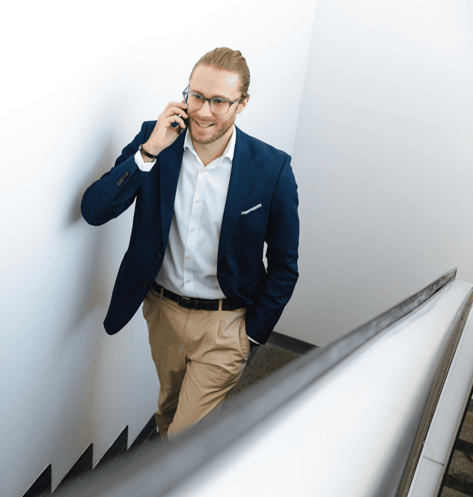 man-with-glasses-in-suite-calling-while-walking-on-the-stairs